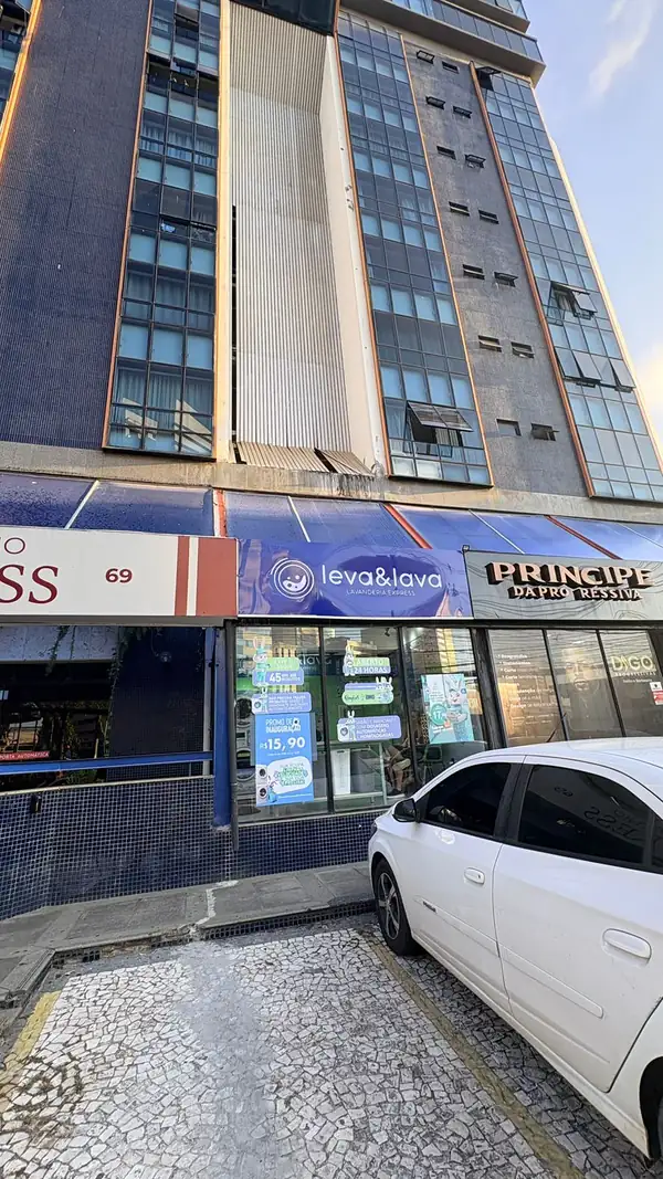 Prédio Edif. Express Flat visto da calçada, com a loja Leva & Lava no térreo e vagas de estacionamento em frente