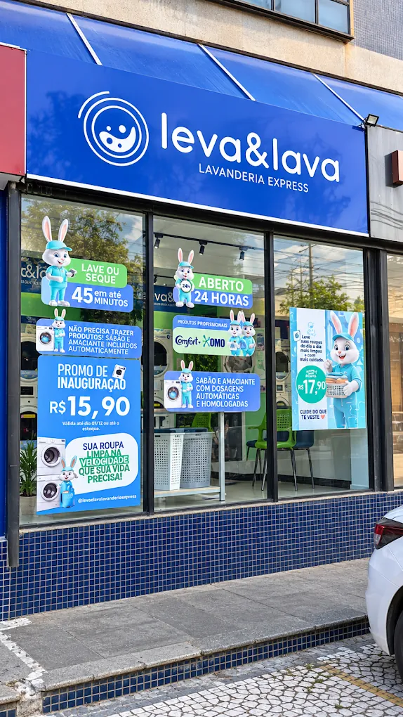 Fachada da Leva & Lava Lavanderia Express no Caminho das Árvores, com letreiro azul e vitrine anunciando lavagem em até 45 minutos, aberto 24 horas e promoção de inauguração de R$ 15,90
